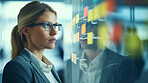 Woman looking and brainstorming with ideas on glass board and sticky note