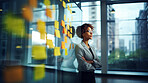 Woman looking and brainstorming with ideas on glass board and sticky note