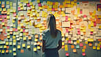 Woman looking and brainstorming with ideas on glass board and sticky note