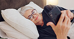Cellphone, relax and senior woman in bed networking on social media, mobile app or internet. Technology, rest and elderly female person in retirement scroll on website with phone in bedroom at home.