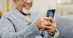 Senior man, happy and phone on sofa with texting, reading or typing for contact in home living room. Elderly person, smartphone and smile for notification, social media app and relax on lounge couch