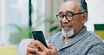 Senior man, smile and phone on sofa with texting, reading or click for contact in home living room. Elderly person, smartphone and happy for notification, social network app or relax on lounge couch
