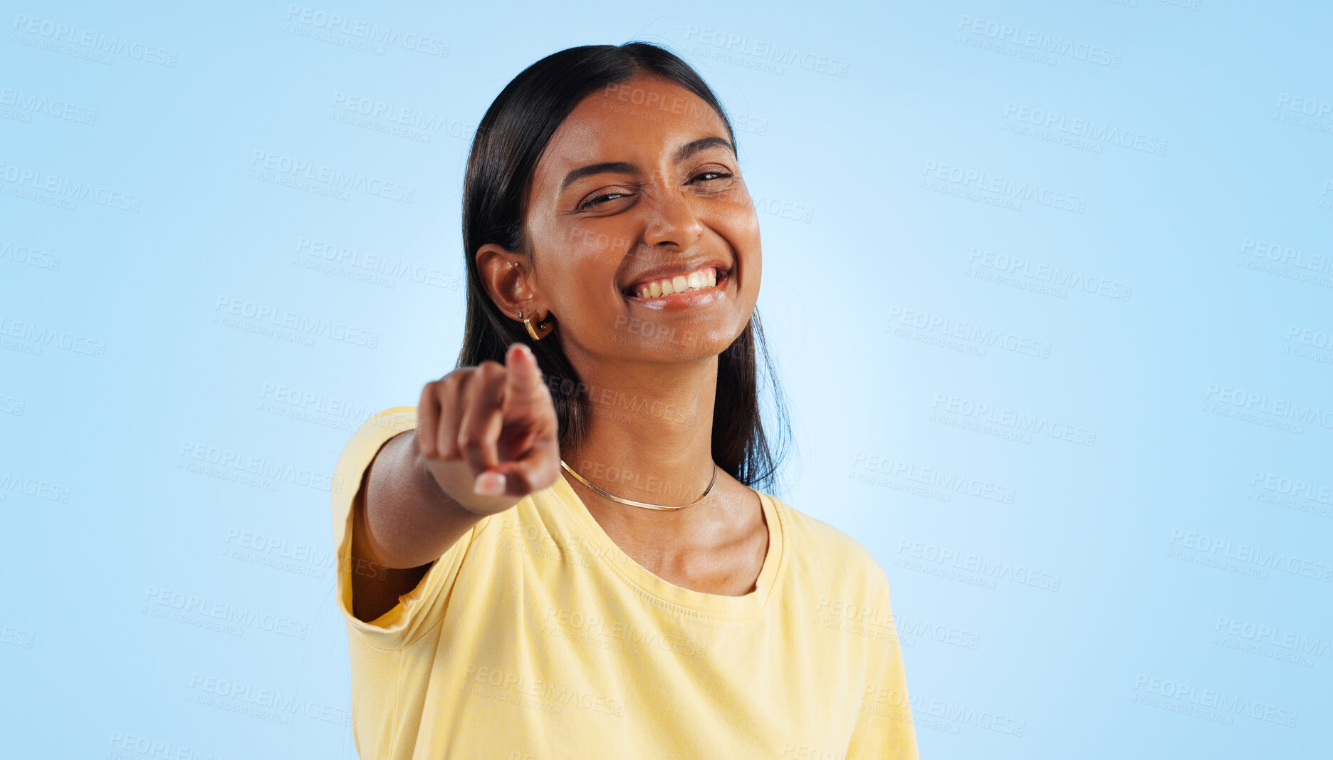 Buy stock photo Woman, portrait and pointing to you in studio for choice, decision of winner and vote for volunteering on blue background. Happy indian model show finger for recruitment, hiring emoji and invitation 