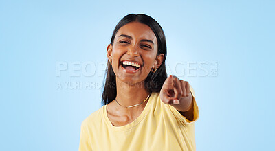 Portrait, pointing to you and woman with a smile, funny and reaction with joy on a blue background. Face, happy person or model with hand gesture, motivation and joke with humor, emotion or laughing