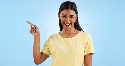 Woman, pointing and portrait with marketing, information and direction for announcement in studio. Blue background, person and promotion with smile and sale with offer and show hand sign of student