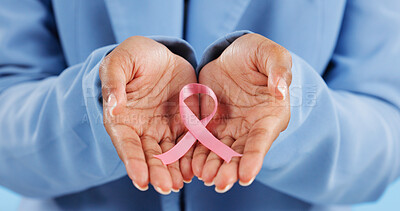 Hands, pink ribbon and breast cancer support with awareness and healthcare icon on blue background. Person in studio, medical symbol and wellness with care, trust and kindness in solidarity campaign