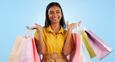 Happy woman, smile and hand with shopping bags in studio for mock up in retail, marketing or promotion on blue background. Indian person, shopaholic and portrait in offer in fashion, cosmetic or sale