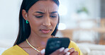 Confused, doubt and woman networking on a phone on sofa in the living room reading bad news. Upset, mad and young Indian female person scroll on social media or the internet with cellphone at home.