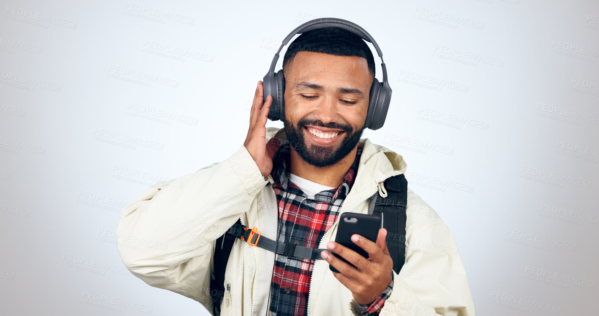 Buy stock photo Man, travel and listening with headphones and phone for music in studio, white background or audio streaming. Radio, podcast or person hiking and relax with hip hop sound, app download or technology 