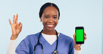 Green screen, okay sign and portrait of doctor with phone for telehealth, wellness app or medical news. Healthcare mockup, clinic website and woman with approval hand emoji on smartphone in studio