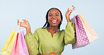 Black woman, shopping bag and retail in portrait with happiness for discount on fashion product in studio. Choice, wealth and commerce with smile for sale, service and gift on blue background