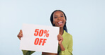 Portrait, sale and poster with a retail black woman in studio on a blue background for promo discount. Smile, shopping and savings with a happy young commercial employee holding a sign for discount