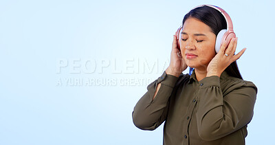 Buy stock photo Woman, headphones and listening to music or podcast, audio and song in studio by blue background. Asian female model, hearing and streaming radio, sound and playlist for peace, chilling and mockup