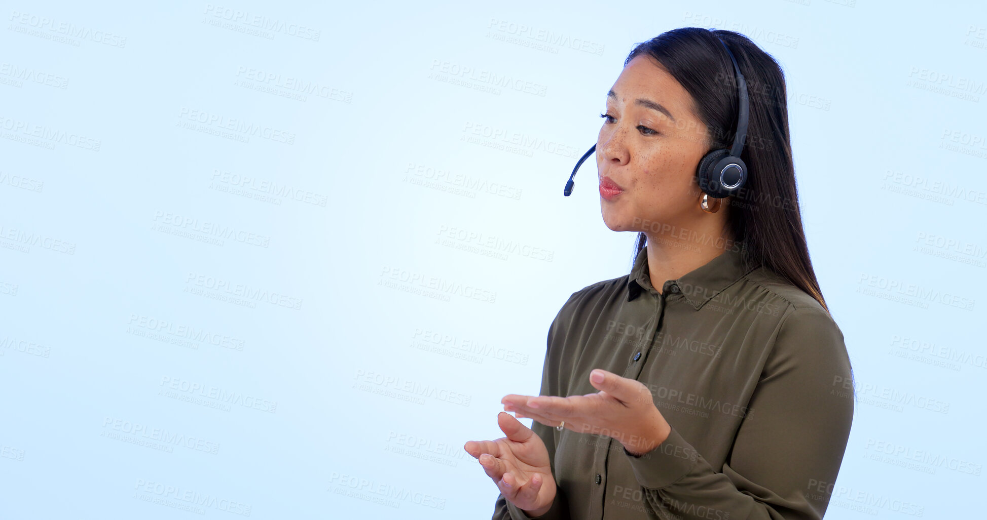 Buy stock photo Space, customer service and support with an asian woman talking in studio on a blue background. Contact us, crm or consulting with a young call center employee telemarketing on a headset for help