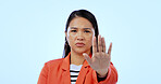Scared, stop sign and portrait of woman in a studio with mad, upset and angry facial expression. Activism, protest and Asian female person with an open palm hand gesture isolated by blue background.