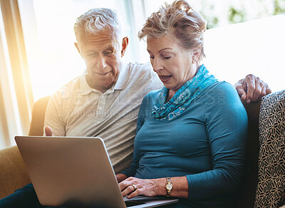 Buy stock photo Shot of a senior couple using a laptop together on the sofa at home