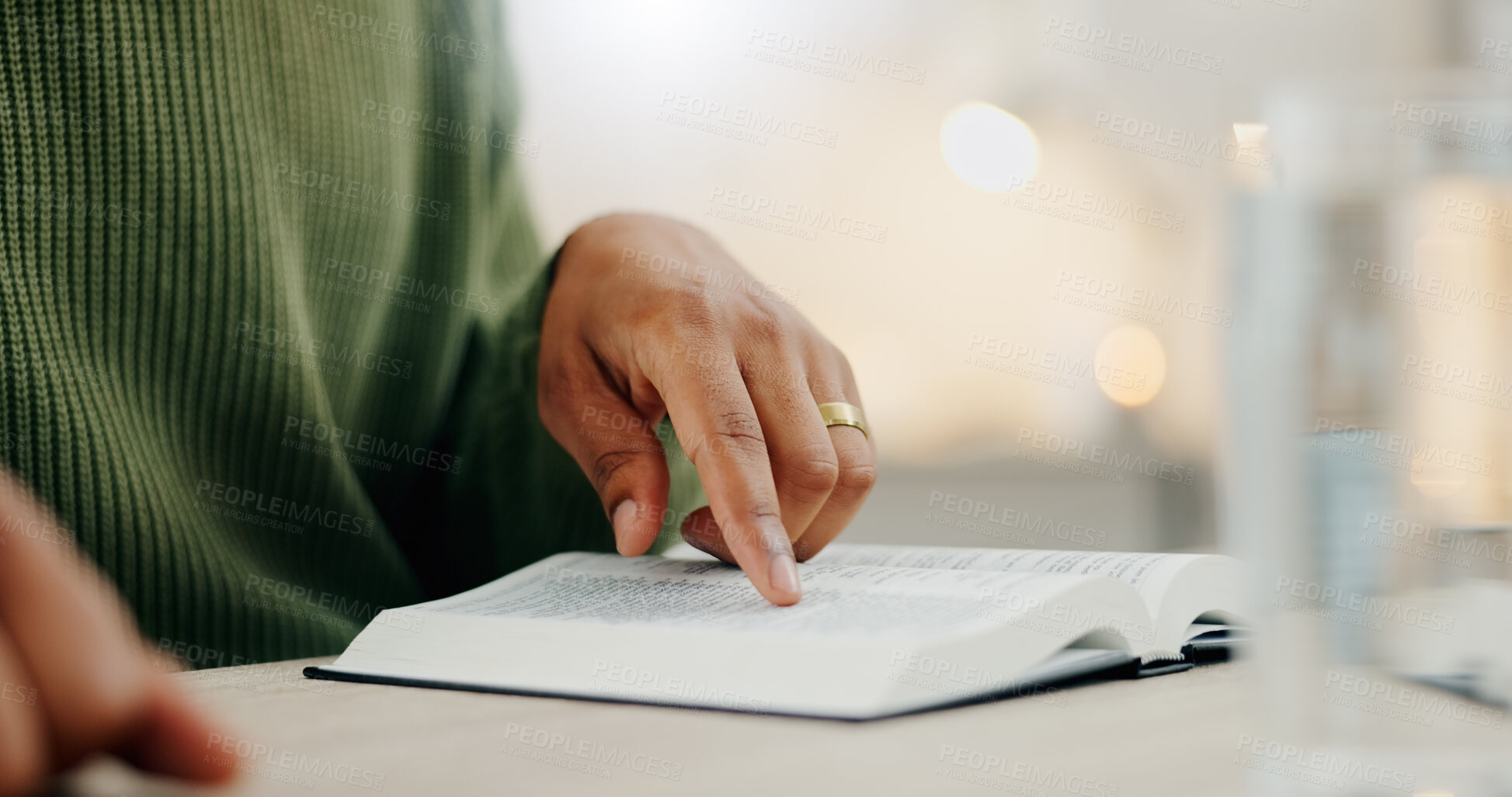 Buy stock photo Closeup hand, reading and a bible for faith, spiritual support or hope from scripture. House, table and a person with a book for worship, trust or education on God, Jesus or learning about religion
