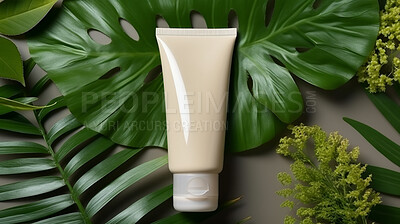 Beige blank tube container on a green leafy backdrop. For organic or eco friendly product