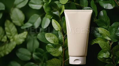 Beige blank tube container on a green leafy backdrop. For organic or eco friendly product
