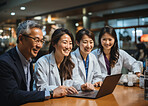 Medical professionals looking at laptop. Sitting at desk smiling. Medical concept.