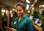 Happy young nurse posing in hospital reception. Phone in hand. Medical concept.