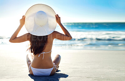 Buy stock photo Rearview shot of a young woman admiring the view while sitting on the beach