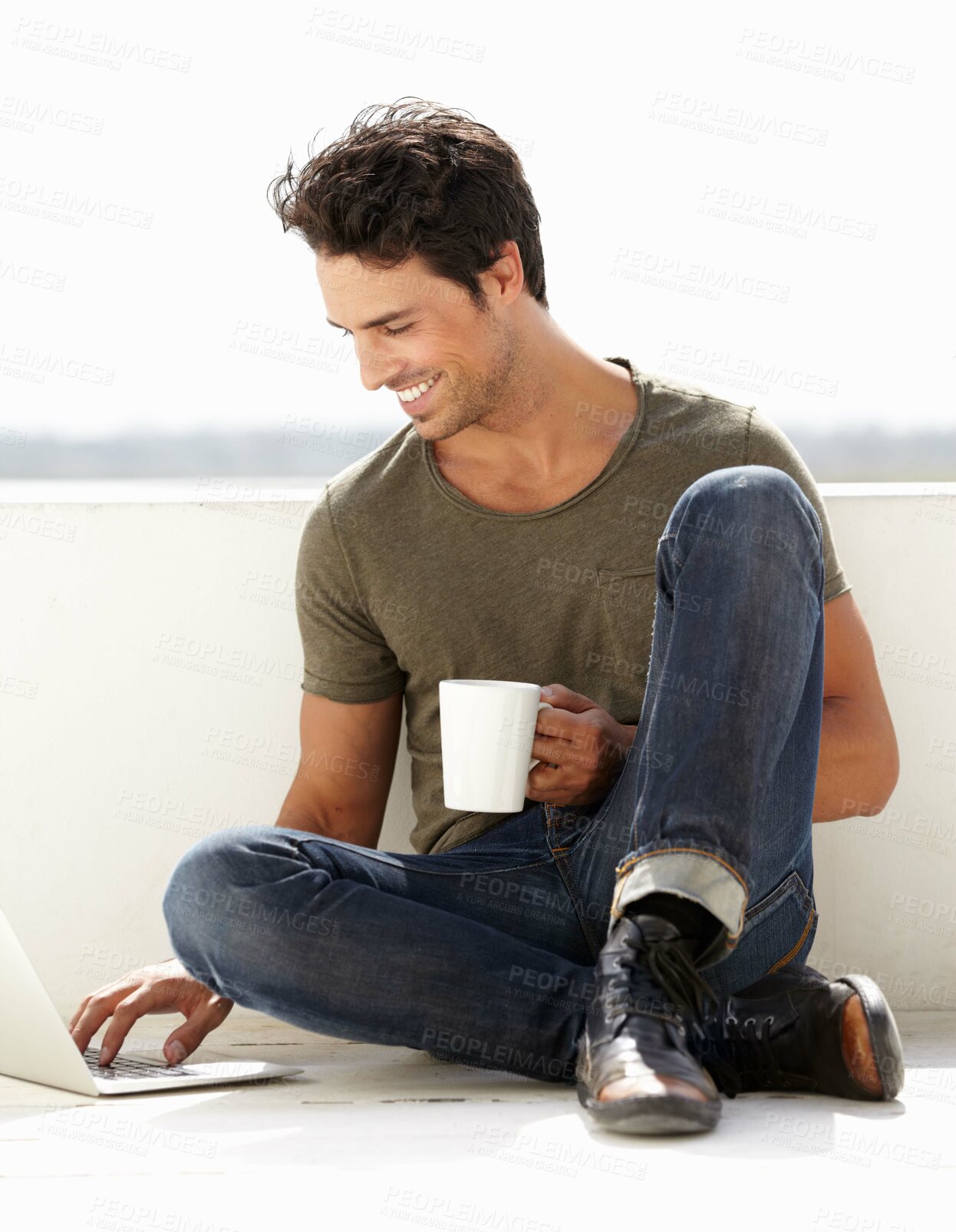 Buy stock photo A handsome young man sitting outside with his coffee while using his laptop