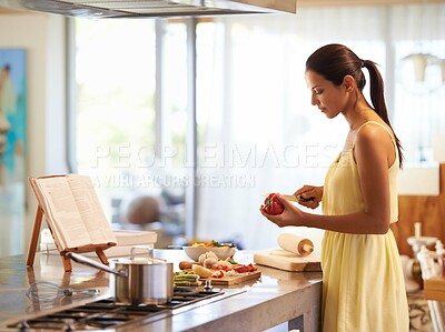 Buy stock photo A young woman cooking from a recipe