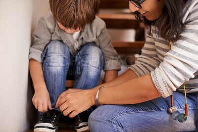Buy stock photo A young mother helping her son tie his shoes