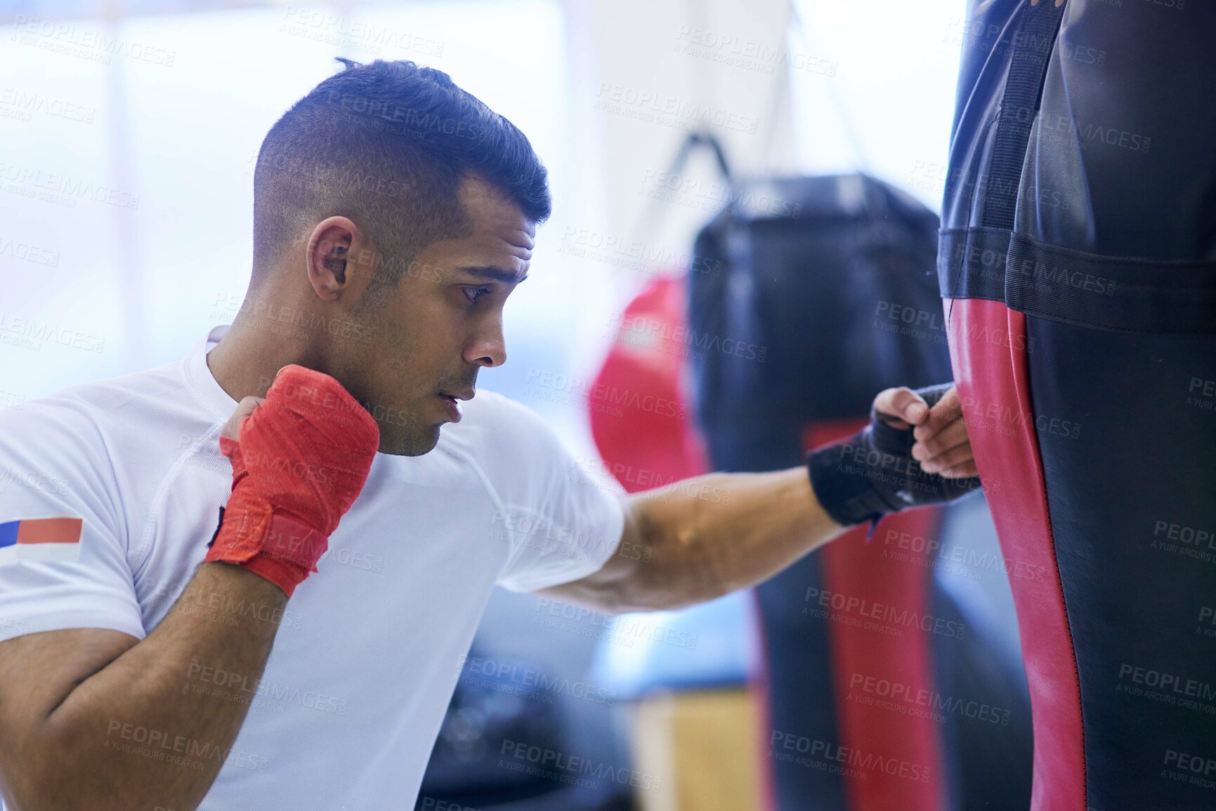 Buy stock photo Shot of a young man going through his boxing routine in the gym