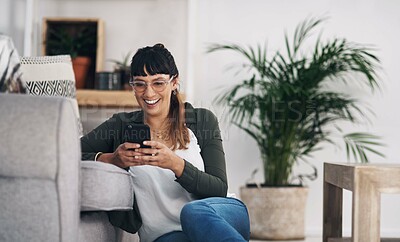 Buy stock photo Cropped shot of an attractive young woman sitting in her living room alone and using her cellphone