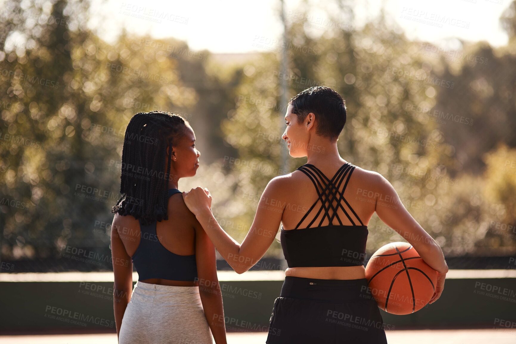 Buy stock photo Cropped shot of two unrecognizable sportswomen bonding after a basketball game together during the day