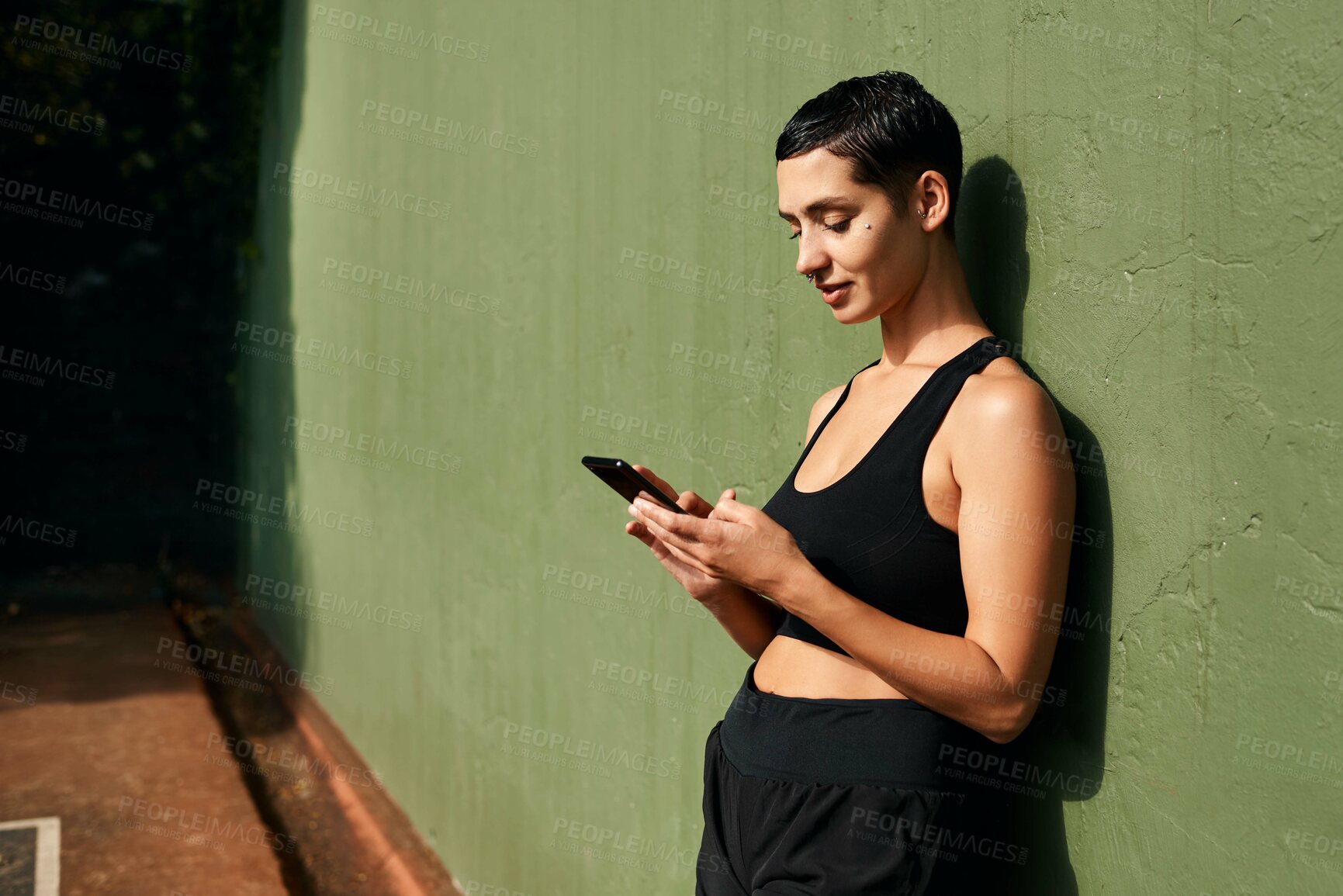 Buy stock photo Cropped shot of an attractive young sportswoman standing alone and using her cellphone after a basketball game