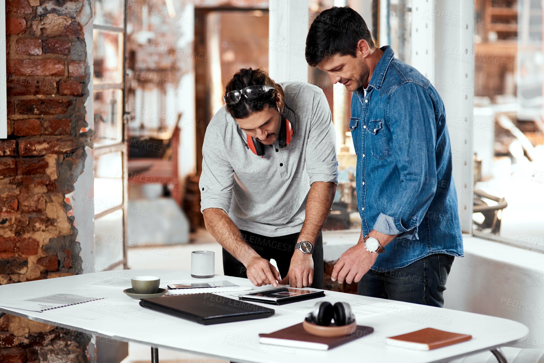 Buy stock photo Cropped shot of two young businessmen working together in an office inside their workshop