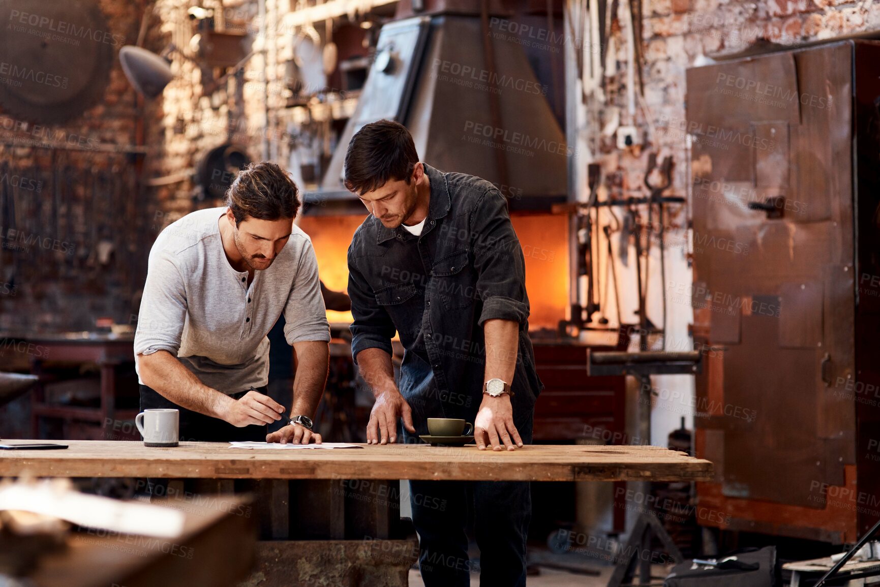 Buy stock photo Cropped shot of two handsome young businessmen working together inside their workshop