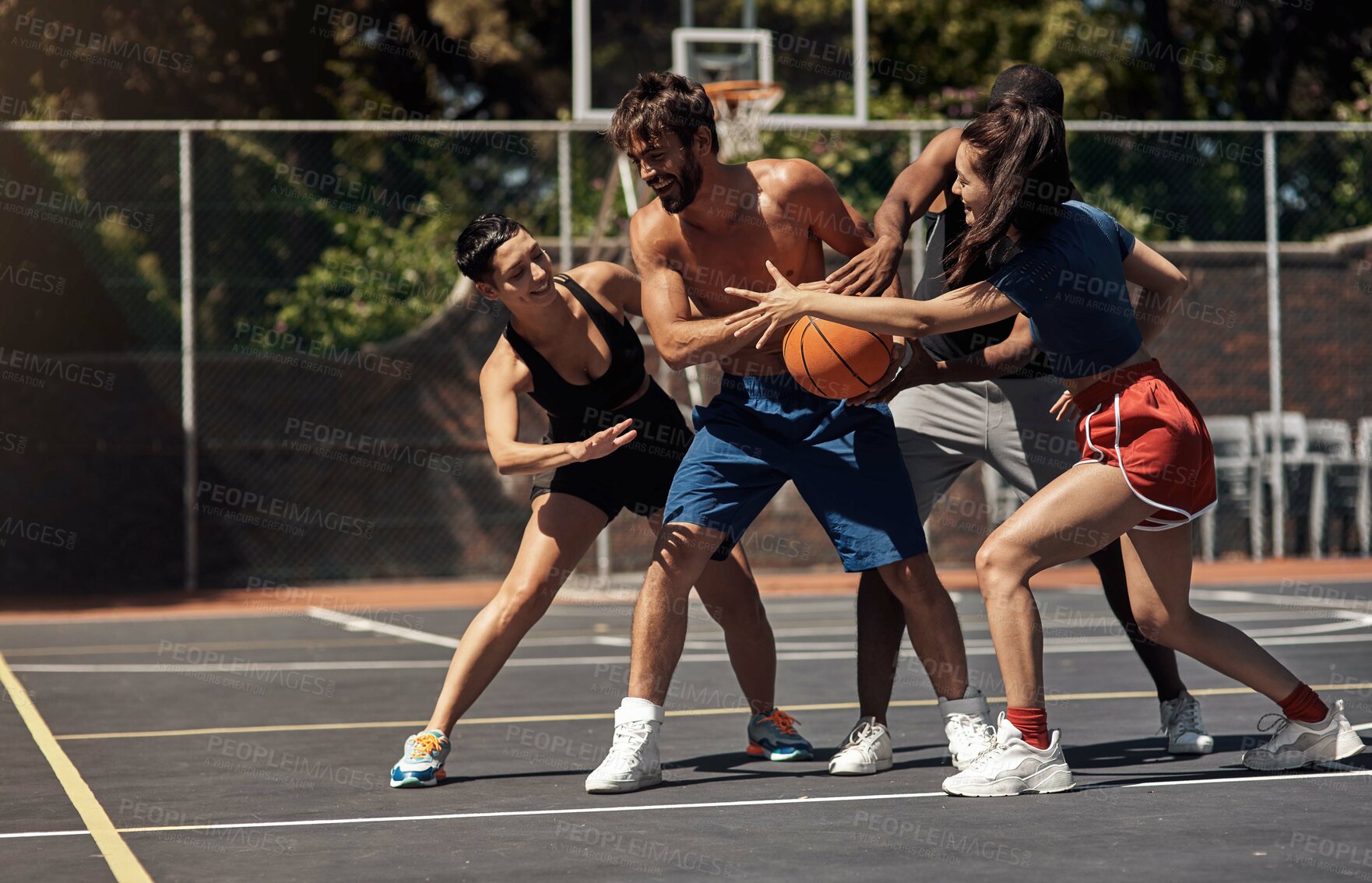 Buy stock photo Shot of a group of sporty young people playing basketball on a sports court