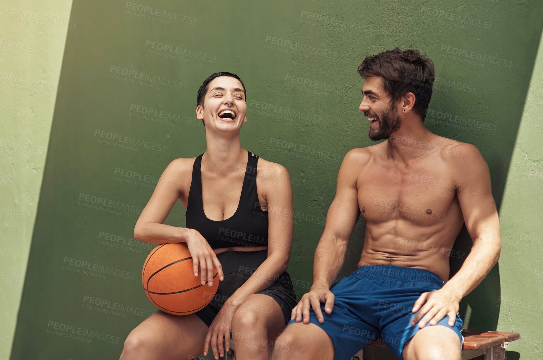 Buy stock photo Shot of two sporty young people taking a break after a game of basketball