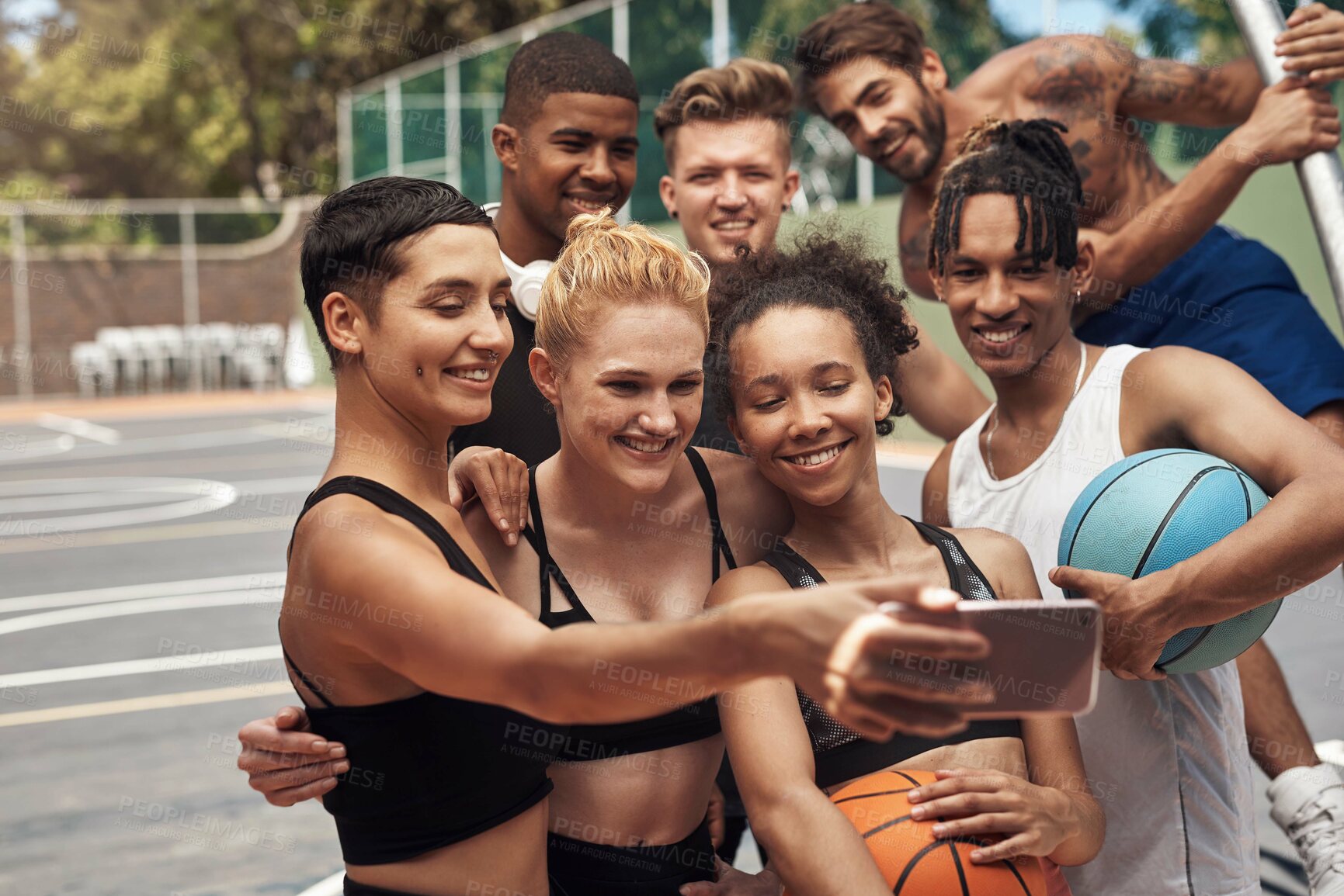 Buy stock photo Shot of a group of sporty young people taking selfies together on a sports court