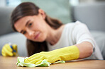 Woman, cloth and gloves for cleaning table with spray, chemical and hygiene in home living room. Girl, cleaner and services with ppe, fabric and product for dust, shine and stop bacteria in house