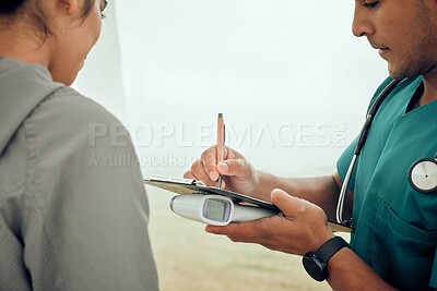 Buy stock photo Cropped shot of a handsome young male physiotherapist filling out paperwork during a session with a female patient outside