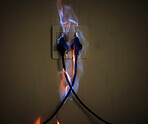 Danger, cables and electrical fire on a plug socket in studio on a dark background for safety. Wall, smoke and power with risk of flame on an outlet for electricity in the circuit of a home closeup