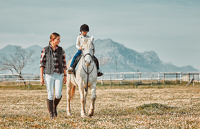 .Child on horse, woman walking on ranch and mountain in background lady and animal walking on field. Countryside lifestyle, rural nature and farm animals, mom teaching girl kid to ride pony in USA.