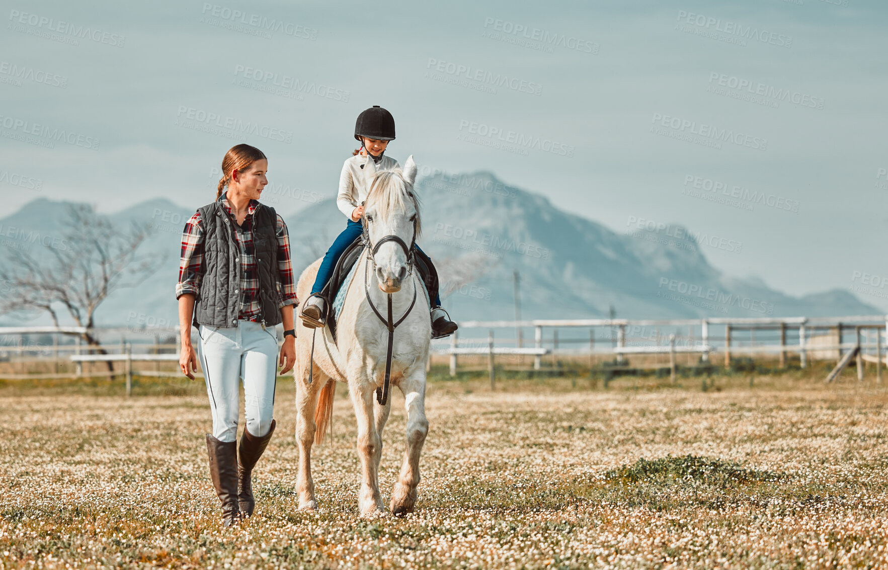 Buy stock photo Child on horse, woman walking on ranch and mountain in background lady and animal walking on field. Countryside lifestyle, rural nature and farm animals, mom teaching girl kid to ride pony in USA.