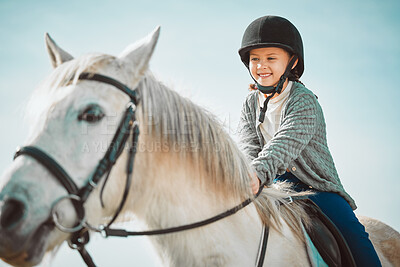 Children, horse and equestrian with a girl riding an animal outdoor on a blue sky background for adventure. Kids, countryside and ranch with a female child enjoying a horseback ride outside in nature