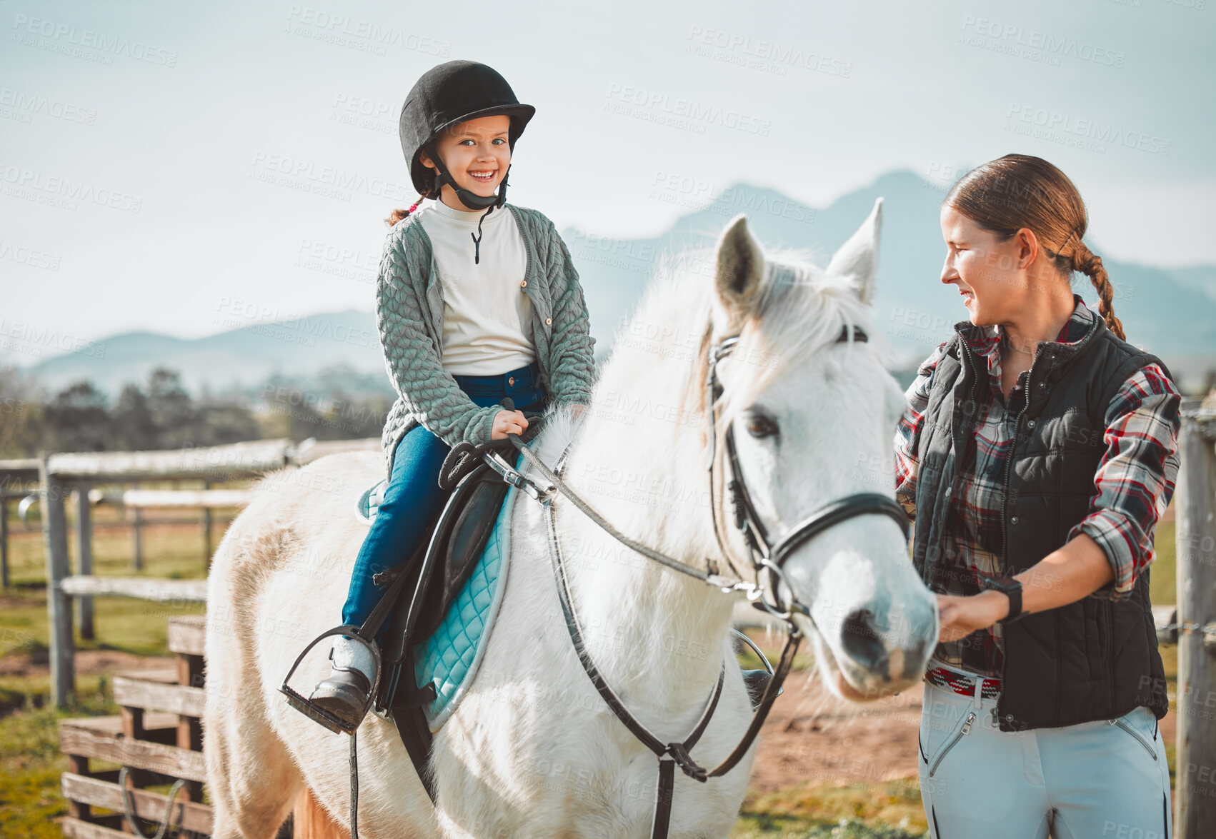 Buy stock photo Happy child on horse, woman with harness on ranch and mountain in background lady and animal walking on field. Countryside lifestyle, rural nature and farm animals, mom girl kid to ride pony in USA.