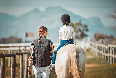 Woman, child on horse and ranch lifestyle with mountain in background lady and animal walking on field from back. Countryside, rural nature and farm animals, mother teaching kid to ride pony in USA.