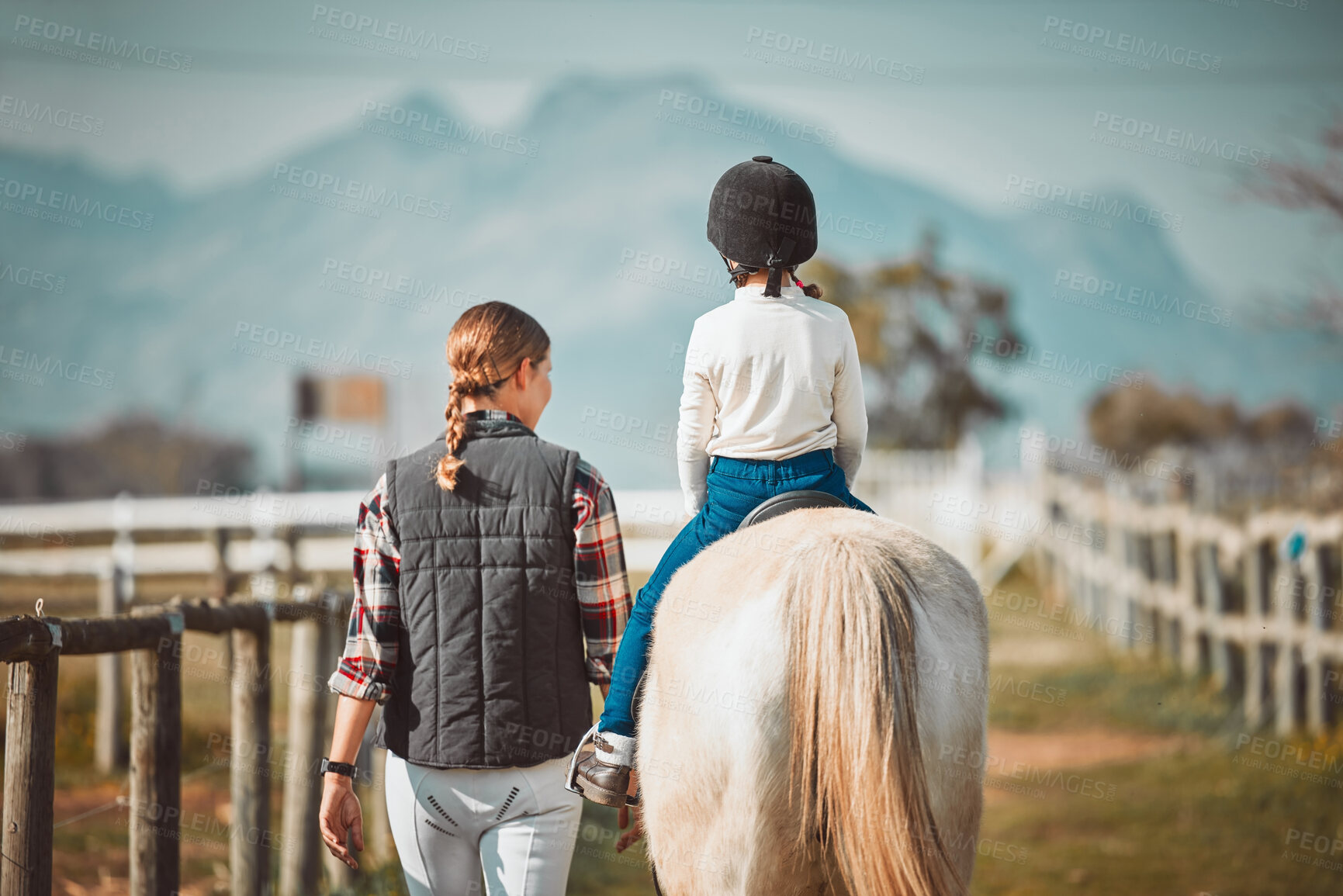 Buy stock photo Woman, child on horse and ranch lifestyle with mountain in background lady and animal walking on field from back. Countryside, rural nature and farm animals, mother teaching kid to ride pony in USA.