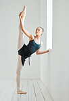 Ballet, woman and leg stretching by window, class and training in dance studio, fitness and exercise. Female person, dancer and strong or flexible, performance and graceful or balance technique