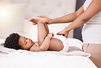 Baby, diaper and changing with hands of a parent in the bedroom of their home for cleaning or care. Family, children and an infant child on the bed for a nappy change with an adult for development