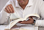 Hands, man and bible study at desk, home and reading for faith, knowledge and spiritual guide. Person, notebook and religion books on table for worship, peace and connection to holy spirit in house